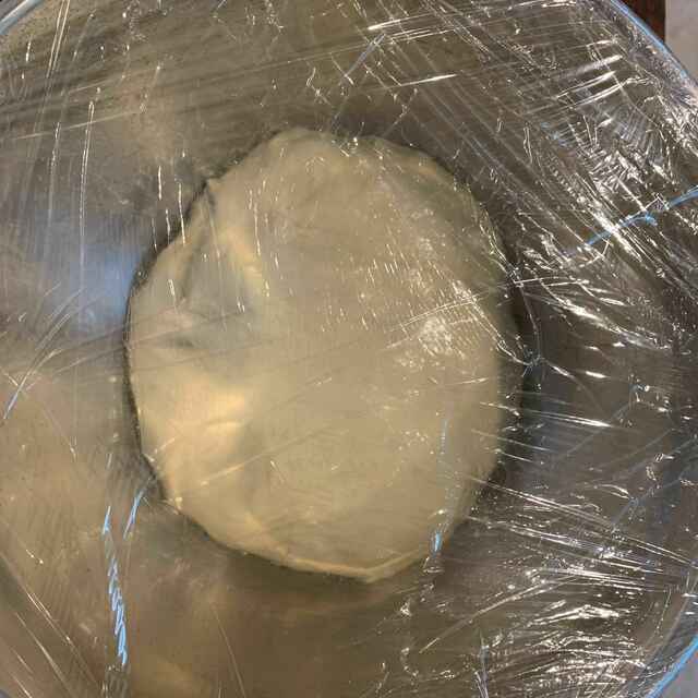 dough ball covered in wrap in an oiled bowl